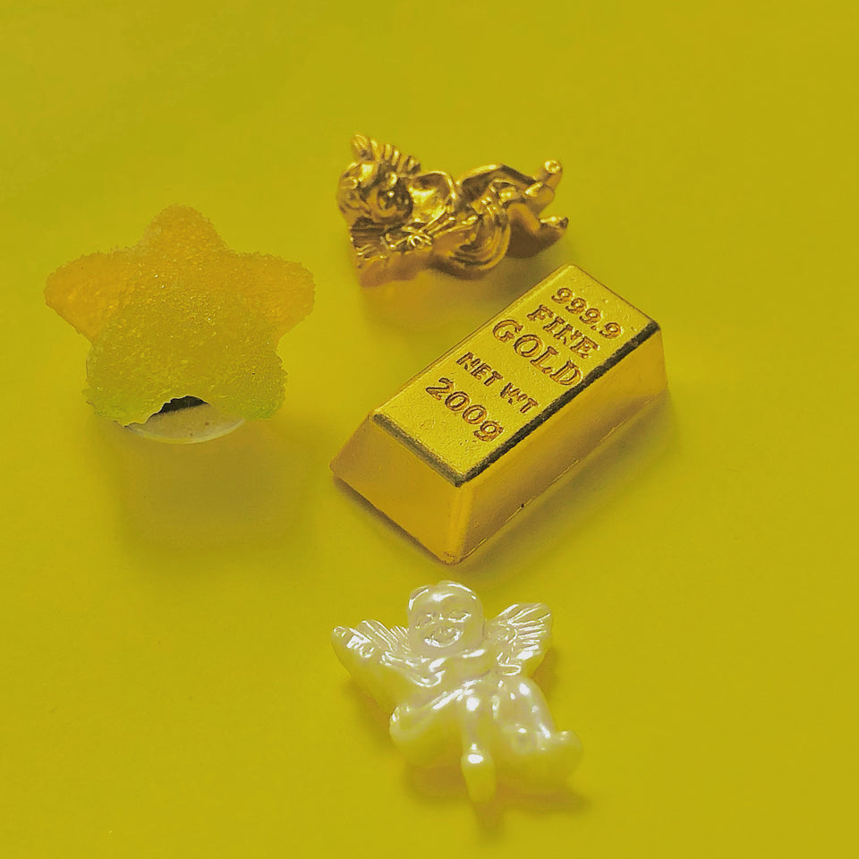 Image showing the gold cherub charm, pearl cherub charm, gold bar charm and yellow and green gradient sugared star charm on a yellow background