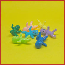 Load image into Gallery viewer, Image of seven miniature plastic babies on a yellow background. The babies are a different colour each; lime green, dark green, light blue, navy blue, purple, yellow and pastel pink.
